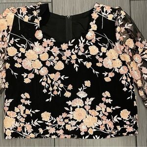 Woman’s black shirt with floral sequins and sheer arms